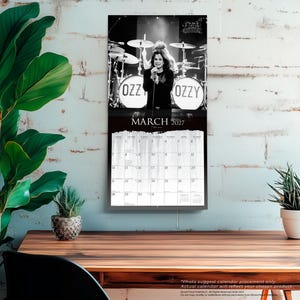 K&ouml;nnte beinhalten: Ein Wandkalender f&uuml;r M&auml;rz 2027 mit einem Schwarz-Wei&szlig;-Foto von Ozzy Osbourne bei einem B&uuml;hnenauftritt mit einem Schlagzeug im Hintergrund. Das Kalenderraster zeigt die Tage des Monats deutlich unter dem Bild des Musikers an.