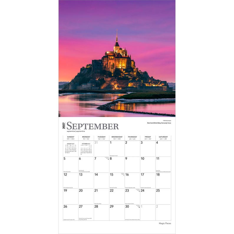 May include: A 2027 wall calendar page for September featuring a photograph of Mont Saint-Michel in France at sunset. The image shows the abbey illuminated against a vibrant pink and purple sky, with the structure reflected in the water below.