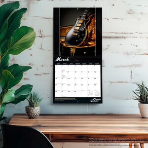 May include: A wall calendar for the month of March featuring a glossy black electric guitar with gold hardware resting in an open hardshell case. The calendar grid displays dates for the month, with the text Electric Guitars at the bottom.