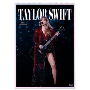Puede incluir: Un calendario oficial de Taylor Swift 2027 con una fotograf&iacute;a de la artista actuando en el escenario. La artista viste un abrigo largo de lentejuelas rojas y toca una guitarra ac&uacute;stica negra sobre un fondo oscuro con efectos de luz azul.