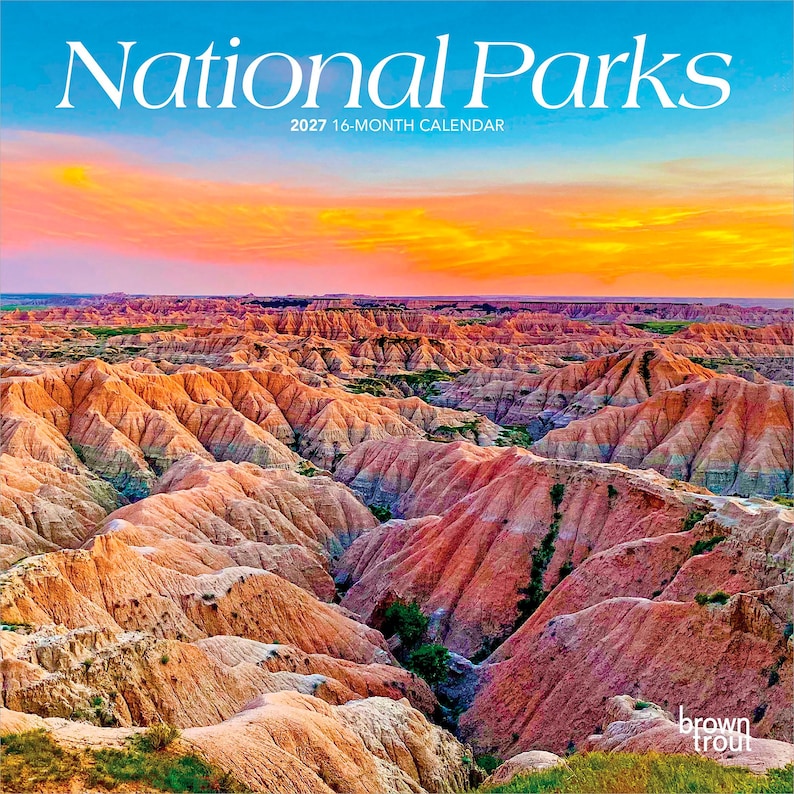 Może przedstawiać: 16-miesięczny kalendarz na 2027 rok zatytułowany National Parks, przedstawiający krajobraz warstwowych, kolorowych formacji skalnych pod niebem o zachodzie słońca w odcieniach pomarańczu i ż&oacute;łci. W prawym dolnym rogu widnieje napis Brown Trout.