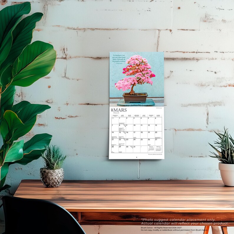 Peut inclure: Un calendrier mural pr&eacute;sentant une photographie d'un bonsa&iuml; aux fleurs roses dans un pot rectangulaire. La page du calendrier affiche le mois de mars, avec une grille de dates et le texte 'MARS' et 'March' imprim&eacute;s en haut de la section.
