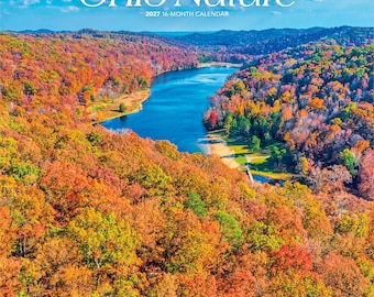 Puede incluir: Un calendario de 16 meses para 2027 titulado Ohio Nature que presenta una fotografía aérea de un río azul serpenteante rodeado de densos bosques con follaje otoñal vibrante en tonos naranja, rojo y amarillo bajo un cielo azul claro.