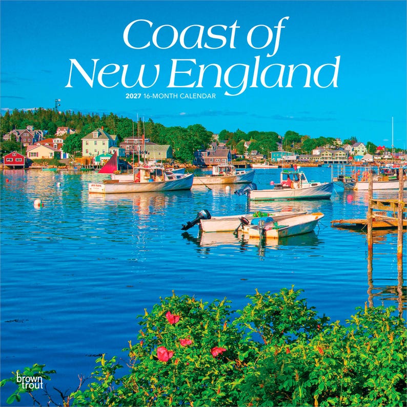 May include: A 2027 16-month calendar titled Coast of New England featuring a vibrant coastal harbour scene with multiple white boats floating on deep blue water, colourful houses along the shoreline, and bright pink flowers in the foreground.