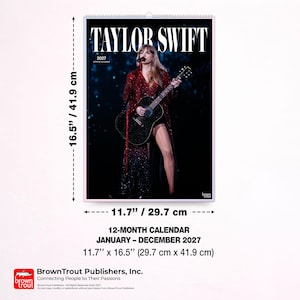 Puede incluir: Un calendario de pared de 12 meses de Taylor Swift para 2027 con una fotograf&iacute;a de la artista tocando la guitarra. El calendario mide 29,7 cm por 41,9 cm. El texto dice Taylor Swift 2027 Official Calendar y BrownTrout.