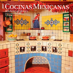 May include: A 2027 wall calendar titled Cocinas Mexicanas Kitchens of Mexico featuring a photograph of a tiled kitchen with yellow and blue accents, a central figurine, hanging dried peppers, green spice shelves, and a bowl of oranges.