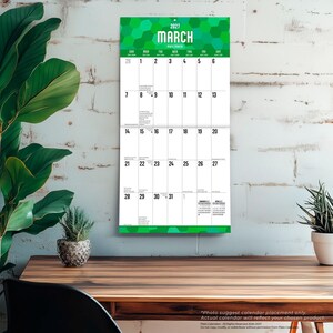 May include: A vertical wall calendar for March 2027 featuring a green hexagonal pattern at the top and bottom. The calendar displays the month name in large white text, followed by a grid of days from the 1st to the 31st with small text entries.