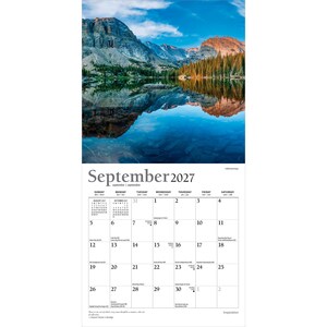 Op de afbeelding: Een wandkalender voor september 2027 met een landschapsfoto van een bergketen die weerspiegelt in een helderblauw meer. Het kalenderraster toont de dagen van de maand met kleine tekst voor feestdagen en een citaat onderaan.