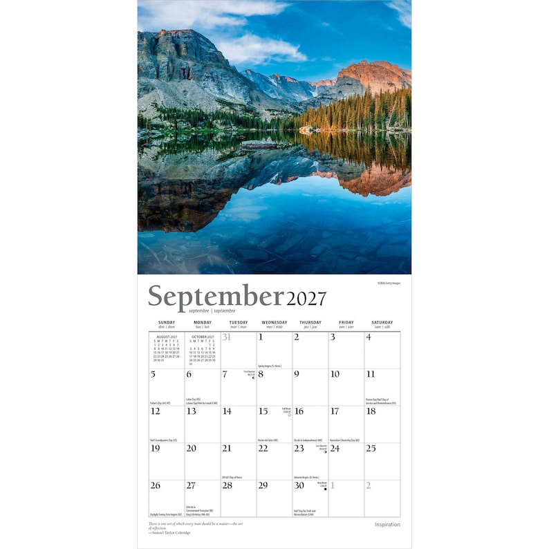 Op de afbeelding: Een wandkalender voor september 2027 met een landschapsfoto van een bergketen die weerspiegelt in een helderblauw meer. Het kalenderraster toont de dagen van de maand met kleine tekst voor feestdagen en een citaat onderaan.