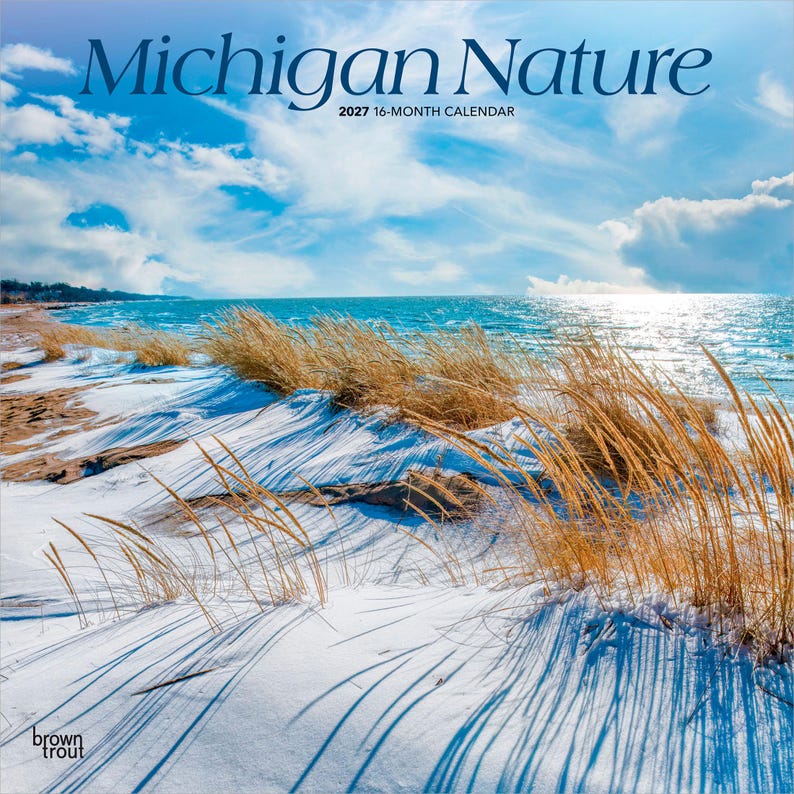 May include: A 2027 16-month calendar titled Michigan Nature featuring a photograph of a snowy beach with golden dune grass, a blue lake, and a bright sky with white clouds. The text BrownTrout is printed in the bottom left corner of the cover.