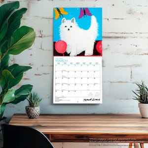 Puede incluir: Un calendario de pared para marzo de 2027 con una pintura de arte popular de un gato blanco esponjoso con ojos verdes de pie entre dos objetos circulares rojos sobre un fondo azul brillante con una mariposa amarilla y una rosa sobre el gato.