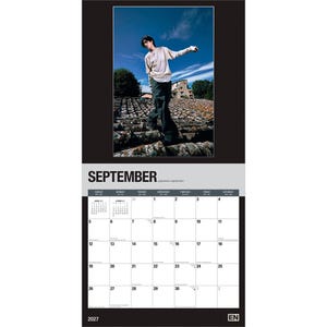 May include: A 2027 wall calendar for the month of September featuring a photograph of a person standing on a tiled roof against a blue sky. The calendar grid displays the days of the month with black text on a white background and the year 2027.