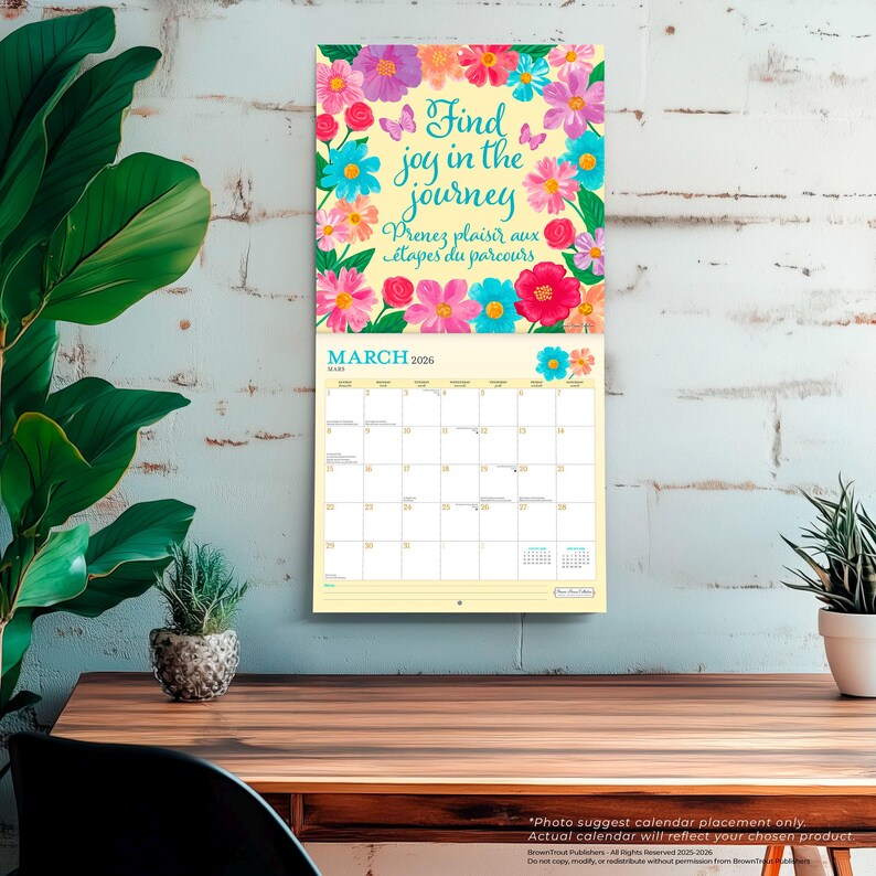 Puede incluir: Un calendario de pared para marzo de 2026, con un dise&ntilde;o floral y el texto "Find joy in the journey" en ingl&eacute;s y franc&eacute;s. El calendario tiene un fondo amarillo claro y est&aacute; decorado con flores coloridas.