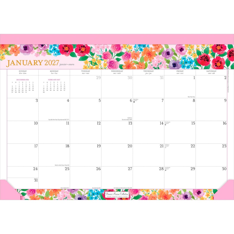 May include: A January 2027 desk calendar featuring a vibrant floral border with pink, orange, purple, and blue flowers. The top and bottom edges are framed in solid pink. The grid displays dates, days of the week, and small monthly calendars.