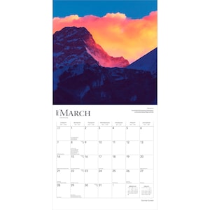 May include: A 2027 wall calendar for the month of March featuring a photograph of a snow-capped mountain peak at sunset with vibrant orange and pink clouds above. The calendar grid displays dates from the 1st to the 31st with black text on white.