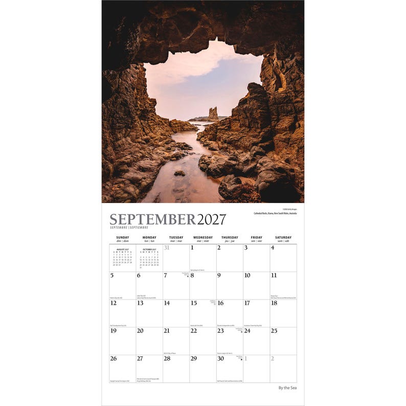 May include: A wall calendar page for September 2027 featuring a photograph of a rocky coastal cave opening looking out toward a distant sea stack under a pale sky. The grid displays the month, days of the week, and dates in black text.