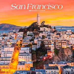 May include: A 2027 16-month calendar titled San Francisco featuring a photograph of the city skyline at sunset. Coit Tower stands prominently on a hill above dense residential buildings, illuminated by a vibrant orange and yellow sky.