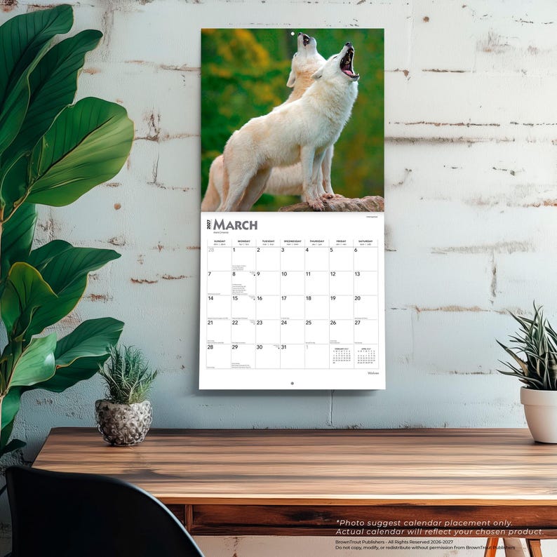 May include: A wall calendar for March 2023 featuring a photograph of two white wolves howling against a blurred green forest background. The calendar grid displays the days of the month with clear black text on a white background, including small calendars for February and April 2023.
