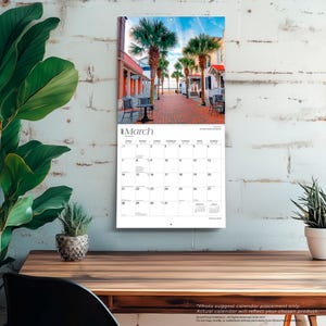 Pode incluir: Um calend&aacute;rio de parede para mar&ccedil;o de 2024 com uma fotografia de um caminho pavimentado com tijolos, ladeado por palmeiras e edif&iacute;cios. A grelha do calend&aacute;rio mostra os dias do m&ecirc;s com texto pequeno para os meses anterior e seguinte.