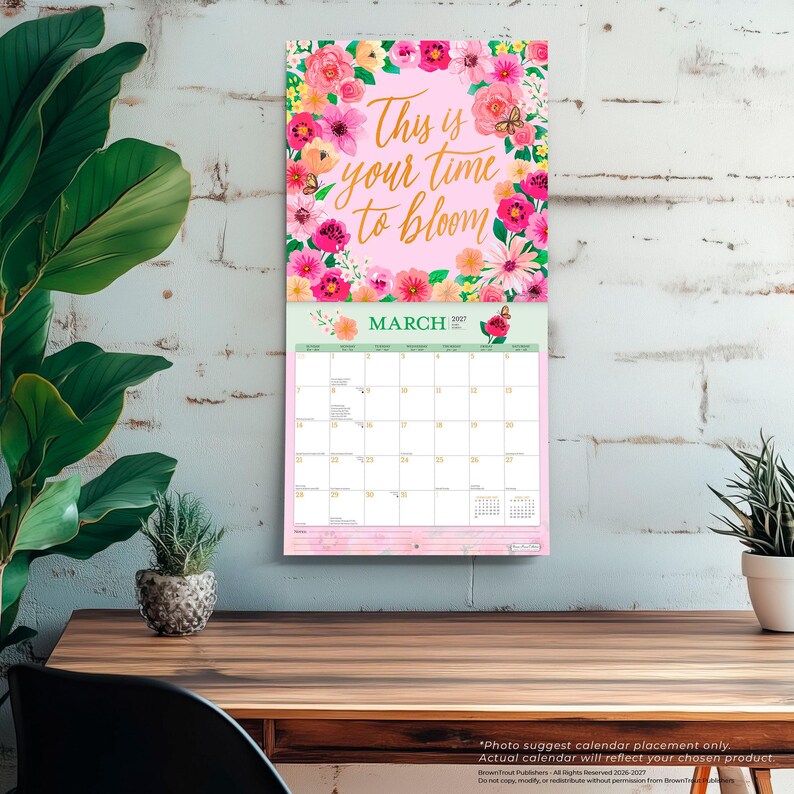 Pu&ograve; includere: Calendario da parete di marzo 2022 con un design floreale con fiori rosa, gialli e fucsia. Il testo "This is your time to bloom" &egrave; scritto in oro. Il calendario &egrave; appeso a un muro di mattoni bianchi.