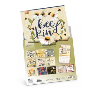 May include: A 2021 wall calendar titled Bee Kind featuring a floral and bee illustration on the cover. The back displays twelve monthly grid previews with various nature-themed designs, including flowers, bees, and seasonal motifs in soft colors.