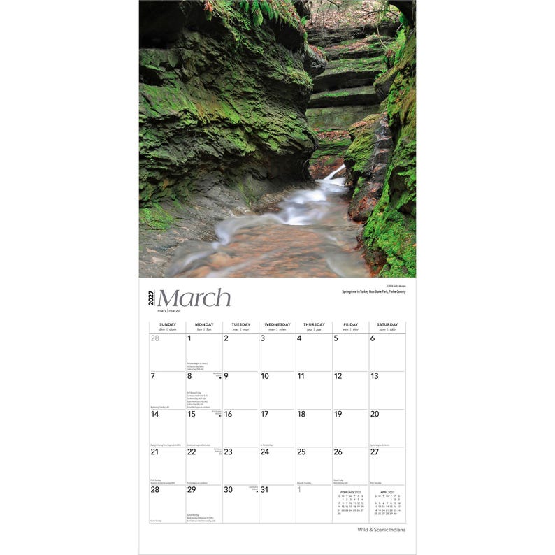 May include: A 2027 wall calendar for the month of March featuring a photograph of a stream flowing through a mossy rock canyon. The calendar grid displays the days of the month with Sunday through Saturday headers and small February and April grids.