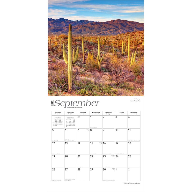 May include: A 2027 wall calendar for the month of September featuring a landscape photograph of Saguaro National Park. The image displays tall green saguaro cacti in a desert landscape with mountains under a blue sky. The calendar grid is white.