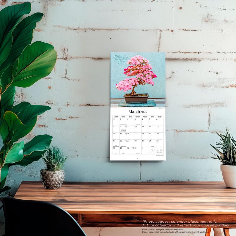 May include: A wall calendar for March 2027 featuring a photograph of a blooming pink bonsai tree in a rectangular brown pot. The calendar grid displays the days of the month clearly, with the text March 2027 printed in a black serif font at the top.