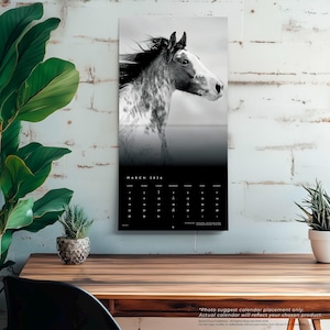 May include: A black and white 2024 calendar featuring a horse's head. The calendar has a black background with white text for the month of March and the days of the month. The calendar is hanging on a white brick wall.