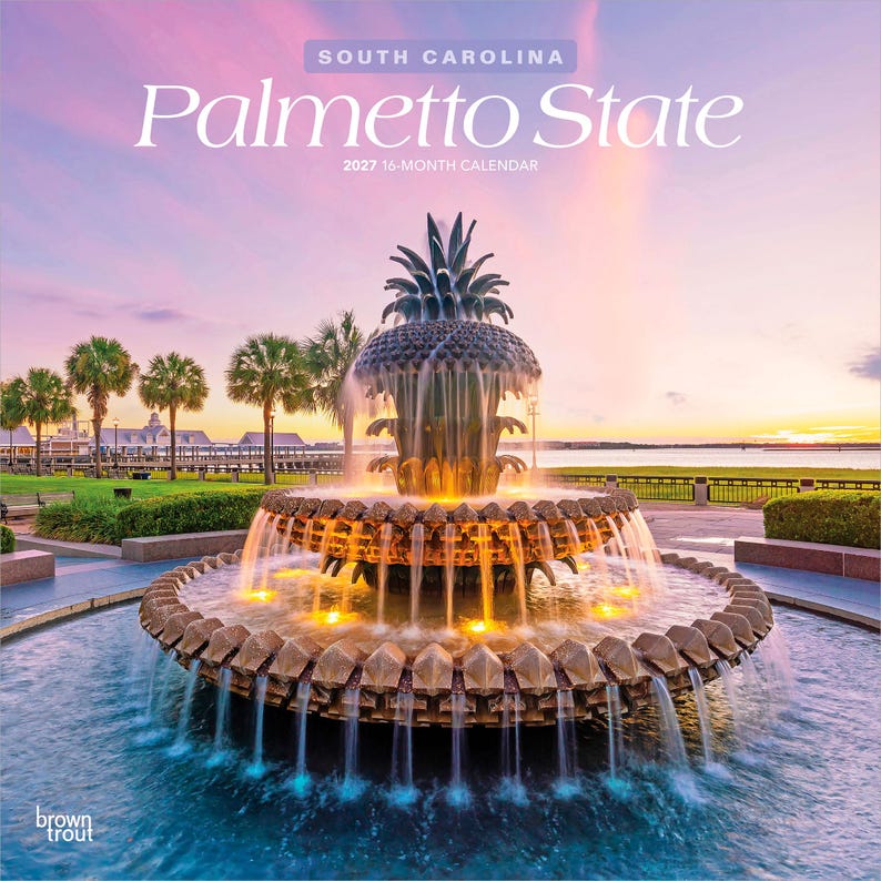 Pode incluir: Um calend&aacute;rio de 16 meses para 2027 intitulado South Carolina Palmetto State com uma fotografia da Pineapple Fountain em Charleston ao p&ocirc;r do sol. A fonte tem n&iacute;veis escalonados com &aacute;gua que cai em cascata para uma piscina.