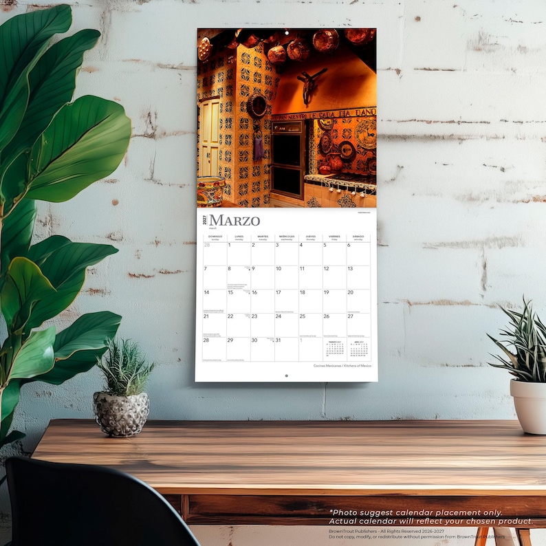 May include: A wall calendar for the month of March 2027 featuring a photograph of a rustic kitchen with patterned tiles, copper cookware, and a crucifix on the wall. The calendar grid displays the days of the month with the title MARZO at the top.