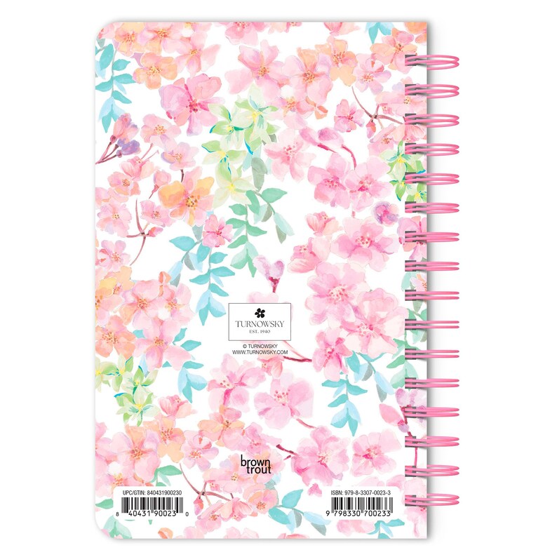 May include: A pink and white spiral bound notebook with a floral pattern. The cover features a watercolor design of pink flowers, green leaves, and a butterfly. The text "TURNOWSKY" and "brown trout" are printed on the cover.