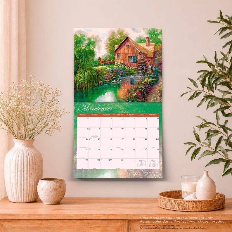 May include: A wall calendar for March 2027 featuring a landscape illustration of a rustic wooden house with a water wheel beside a stream, surrounded by lush green trees and colourful flowers, with a grid layout for the month below the image.