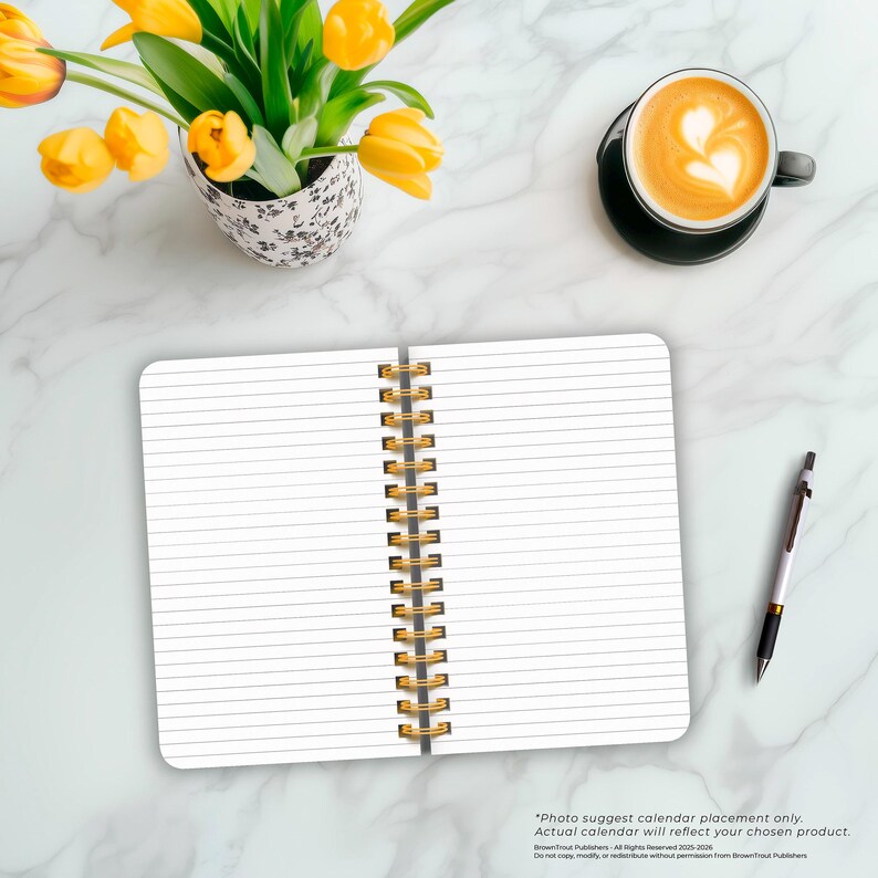 May include: A white spiral bound notebook with lined pages, a gold spiral binding, and a white background. The notebook is open to a blank page. A cup of coffee with a heart design in the foam is in the upper right corner of the image. A yellow pen is in the lower right corner of the image.