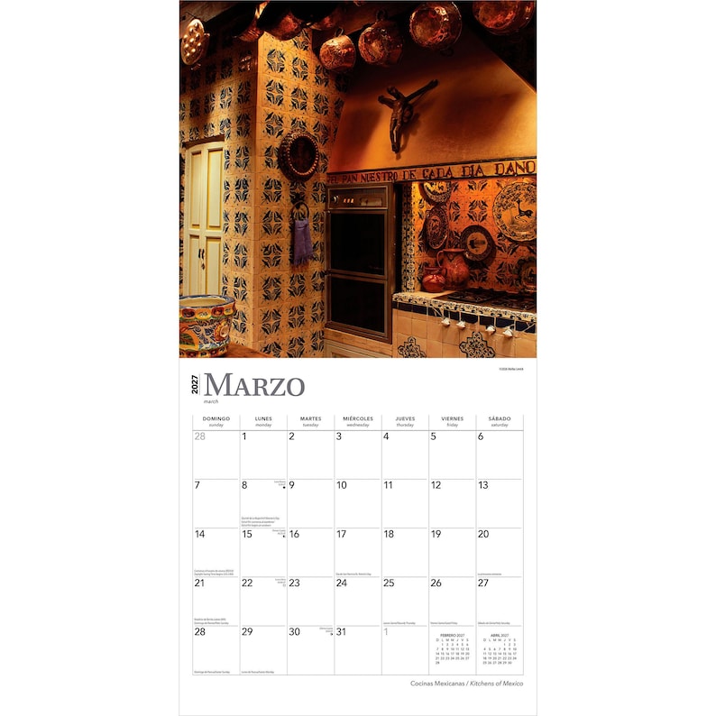 May include: A 2027 wall calendar for the month of March featuring a photograph of a rustic kitchen with blue and white patterned tiles, copper pots hanging from the ceiling, a built-in oven, and a crucifix mounted on the wall above the stove.