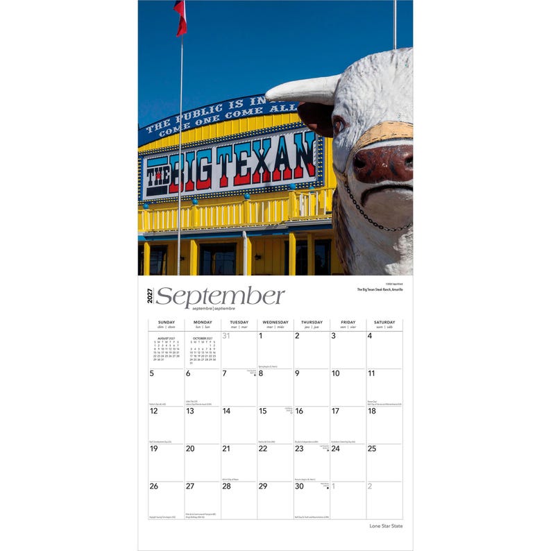 May include: A 2027 wall calendar page for September featuring a photograph of The Big Texan building with a large white bull statue in the foreground. The building is yellow with blue trim and the text THE BIG TEXAN is displayed in bold letters.