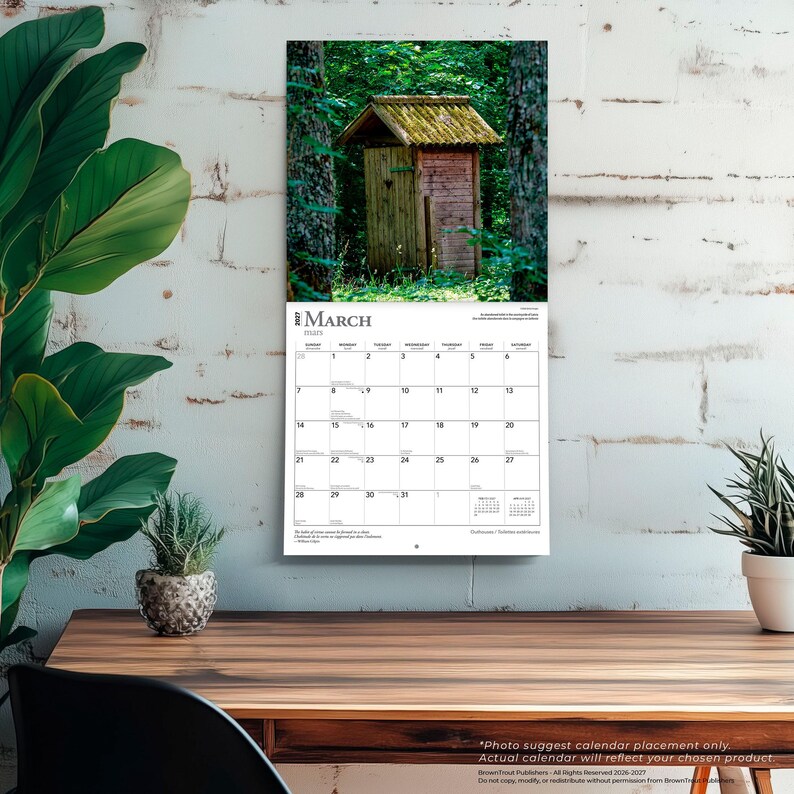 May include: A wall calendar for March 2027 featuring a photograph of a rustic wooden outhouse nestled in a dense green forest. The calendar grid displays the days of the month clearly, with the month name March 2027 printed at the top of the page.