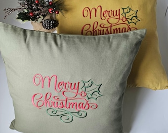 Puede incluir: Dos almohadas decorativas con el texto "Merry Christmas" bordado en rojo y verde. Las almohadas están hechas de una tela suave y texturizada. Una almohada es verde y la otra es amarilla.