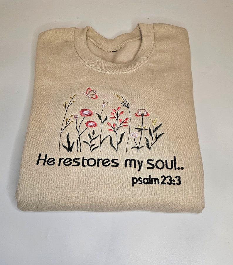 Wildflower embroidered on a sand colour sweatshirt with the inscription: he restored my soul