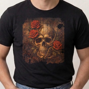 May include: Black t-shirt featuring a skull design with red roses. The skull is detailed with a weathered, vintage aesthetic, and the roses are vibrant against the dark background. The shirt is a classic crew neck.
