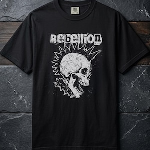 Op de afbeelding: Een zwart t-shirt met korte mouwen en een witte grafische print van een schedel met een hanenkam en een halsband met stekels. Het woord REBELLION staat in een verweerd wit lettertype boven de schedel. Het shirt heeft een ronde hals.