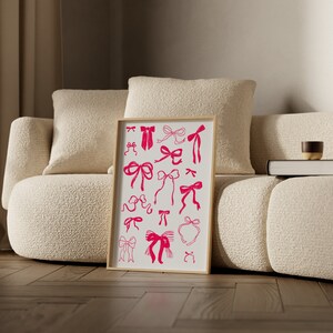 May include: A framed print featuring a collection of pink bow illustrations on an off-white background. The bows vary in style and size, with a simple, graphic design. The print is displayed in a light wood frame, adding a touch of elegance to the artwork.
