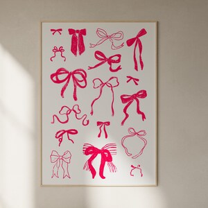 May include: A framed print featuring a collection of pink bow illustrations on a white background. The bows vary in style and size, creating a playful and decorative design. The print is encased in a simple, light-colored frame.
