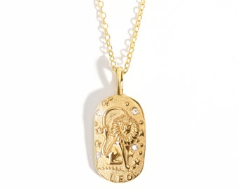 May include: Gold necklace with a rectangular pendant featuring a detailed lion zodiac symbol with small clear stones. The pendant is engraved with the word "LEO".