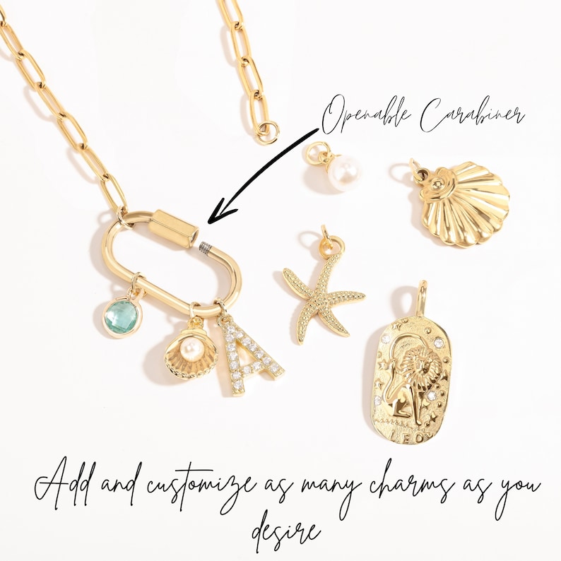 Gold paperclip chain necklace with openable clasp for customization. Includes charms like a cubic zirconia ‘A,’ pearl shell, starfish, Leo zodiac, and birthstone. Easily add or personalize charms for a unique look.