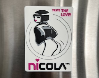 May include: White refrigerator magnet with a black and white illustration of a woman with a pink heart on her chest. The text "Taste the Love!" is in pink and the text "nicola™" is in pink and black.