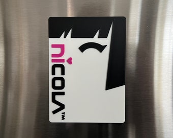May include: A white and black magnet with a pink heart and the text "nicola™" in black. The magnet features a stylized black silhouette of a person with a winking eye.