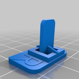 Puede incluir: Un soporte de plástico azul con una base rectangular y un poste vertical. La base tiene la letra "D" en relieve.
