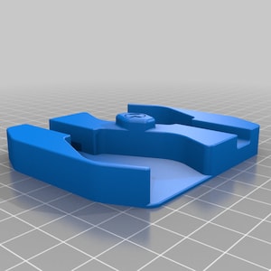 Puede incluir: Un objeto de plástico azul impreso en 3D con un pequeño agujero en el centro. El objeto tiene una forma redondeada y parece ser un soporte o base para un dispositivo pequeño.