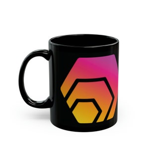May include: Black ceramic mug with a gradient hexagon logo in pink, orange, and yellow. The mug has a curved handle and a glossy finish. The design is centered on the mug's surface. Ideal for hot beverages.